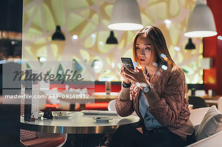 Woman sitting in restaurant, using smartphone