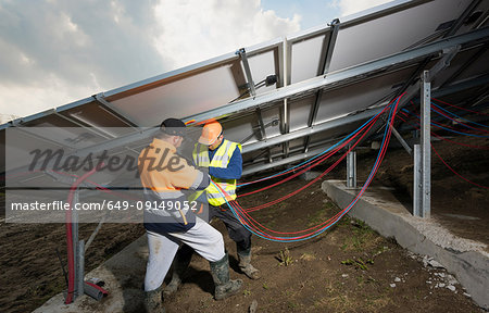 Engineers connecting solar panels on new solar farm, situated on former waste dump