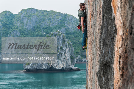 Man rock climbing on limestone rock, Ha Long Bay, Vietnam