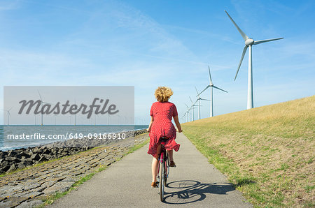 Girl cycling between onshore and offshore wind farm, Urk, Flevoland, Netherlands