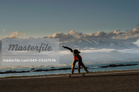 Young boy skateboarding along coastal road, Kaikoura, Gisborne, New Zealand