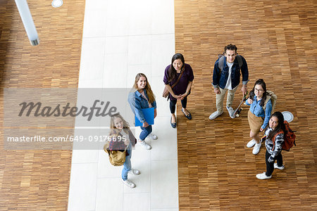 Male and female university students looking up from university lobby, high angle portrait