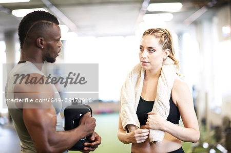 Trainer and female client talking in gym