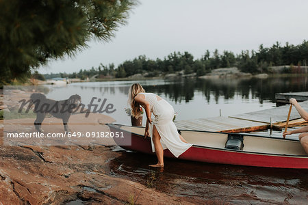 Couple and pet dog getting off boat, Algonquin Park, Canada