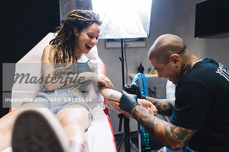 Tattooist drawing on arm of customer