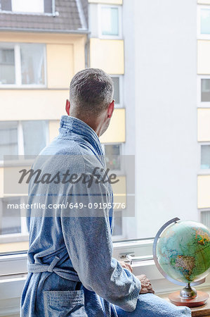 Man looking out of window at apartment block