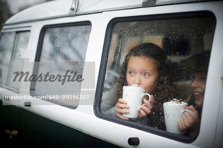 Girls drinking hot chocolate inside camper van