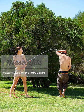 Teenagers playing with water hose