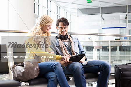 Couple using tablet computer in airport