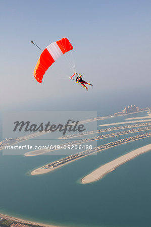 Woman parachuting over rural landscape