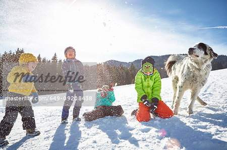 Children and pet dog enjoying playing in snow