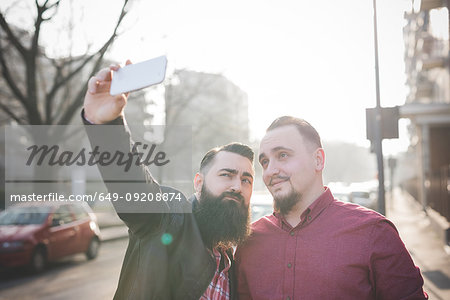 Gay couple taking selfie on pavement