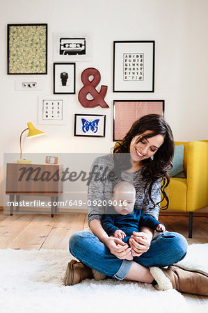 Mother with baby son on lap in living room