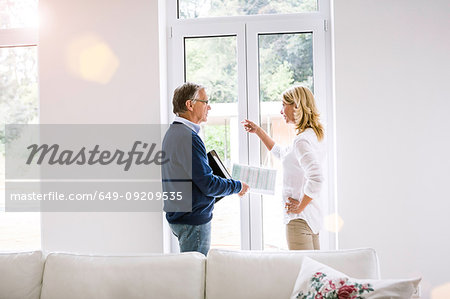 Couple in front of french doors discussing paperwork