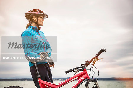 Mature female mountain biker looking out from lakeside