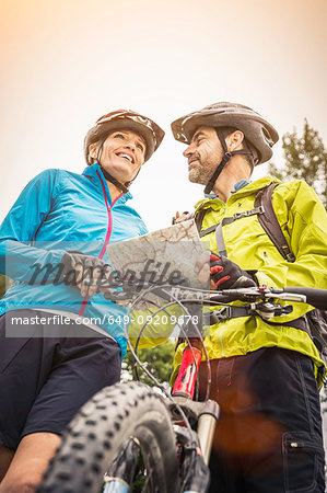 Low angle view of mature mountain biking couple with map
