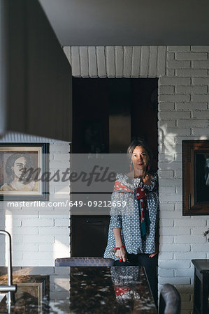 Woman leaning against doorway of kitchen