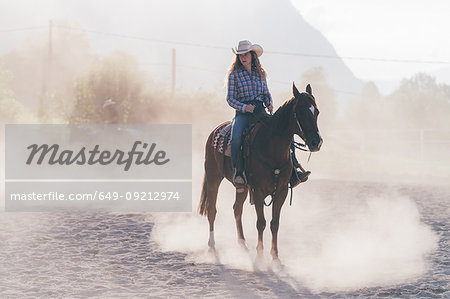 Cowgirl on horse in dusty equestrian arena, Primaluna, Trentino-Alto Adige, Italy