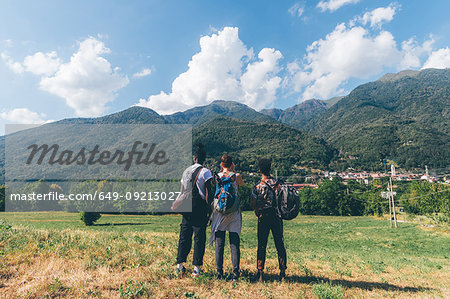 Three young hiking friends looking towards mountains, rear view, Primaluna, Trentino-Alto Adige, Italy