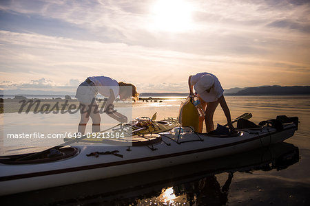 Two female kayakers preparing kayak, Quadra Island, Campbell River, Canada