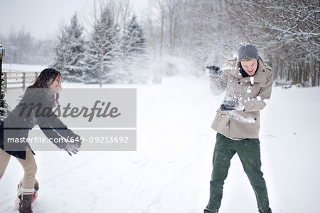 Young couple having snowball fight in snow covered forest, Ontario, Canada