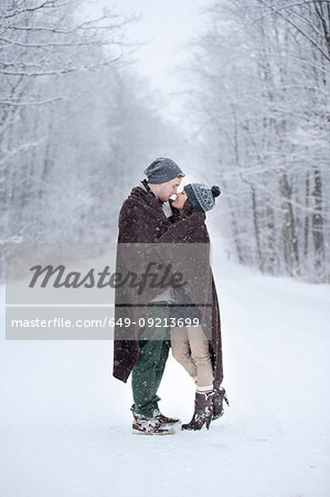 Romantic young couple kissing in snowy forest, Ontario, Canada