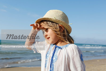 Cute girl on beach shielding her eyes, Castellammare del Golfo, Sicily, Italy