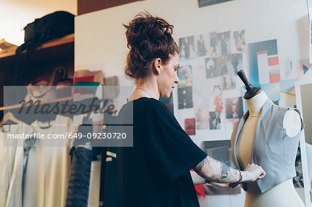 Fashion designer pinning garment onto dressmaker's dummy