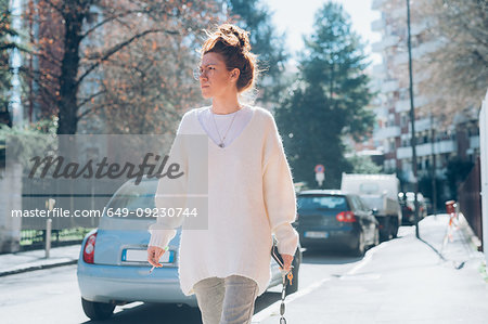 Woman walking on sunny street, Milan, Italy