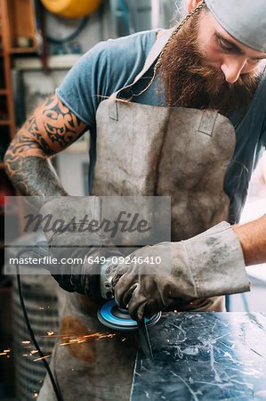 Axe maker using steel grinder in workshop