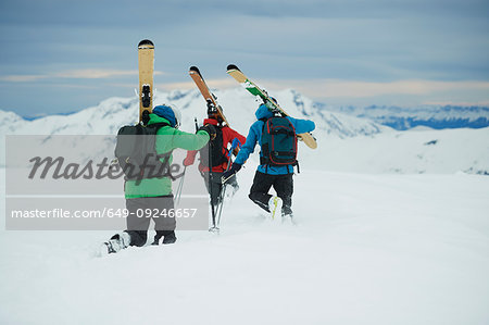 Landscape with three male skiers trudging toward mountain, rear view, Alpe-d'Huez, Rhone-Alpes, France