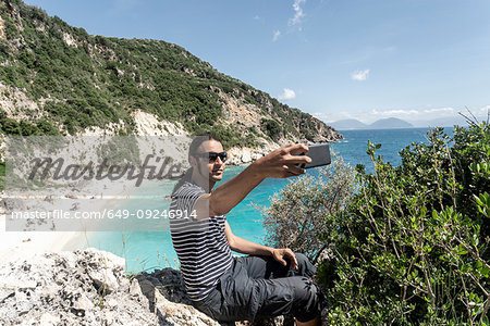 Man taking selfie on cliff top, Lefkada Island, Levkas, Greece