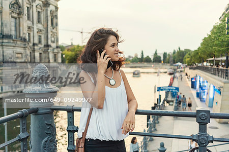 Female student using smartphone by river, Berlin, Germany