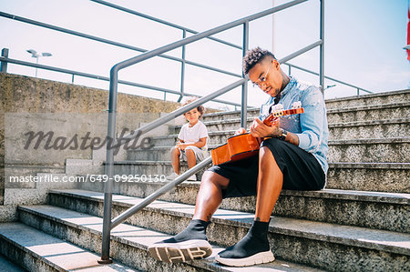 Toddler watching father play guitar on stairway
