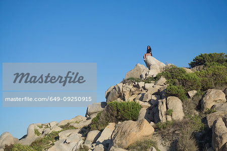 Woman sitting on rock, Villasimius, Sardegna, Italy