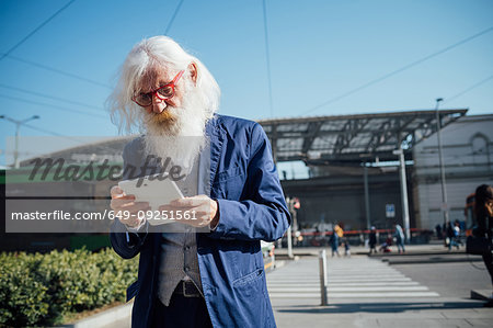 Senior businessman using digital tablet at bus terminal, Milano, Lombardia, Italy