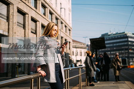 Young woman looking at smartphone at tram station