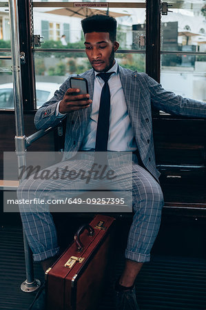 Businessman using smartphone on tram in city