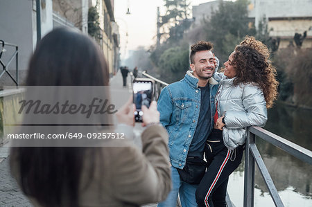 Friends taking photograph by river, Milano, Lombardia, Italy