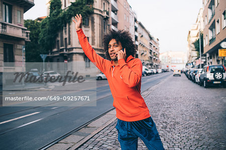 Young man hailing cab in city, Milano, Lombardia, Italy