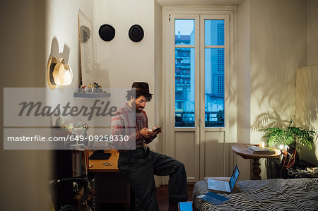 Bearded young man using smartphone on bedroom table
