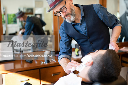 Hairdresser preparing to shave customer's beard in barber shop Hairdresser preparing to shave customer's beard in barber shop
