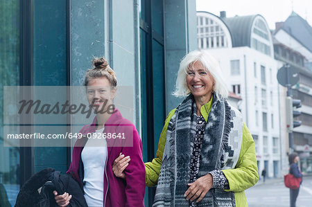 Mature woman and daughter strolling arm in arm on city street, portrait Mature woman and daughter strolling arm in arm on city street, portrait