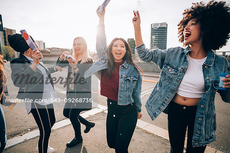 Friends celebrating with confetti and soap bubbles in street, Milan, Italy Friends celebrating with confetti and soap bubbles in street, Milan, Italy