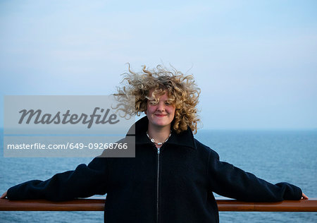 Teenage girl leaning against handrail on windy day Teenage girl leaning against handrail on windy day
