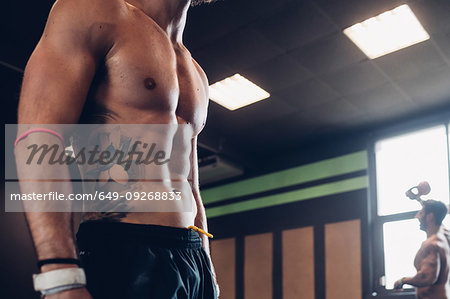 Young tattooed man training in gym, mid section side view Young tattooed man training in gym, mid section side view