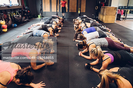 Women training in gym with male trainer, doing push ups