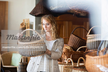 Young woman looking at wickerwork basket in shop Young woman looking at wickerwork basket in shop