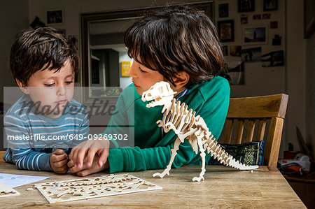 Boy showing brother way to build wooden dinosaur
