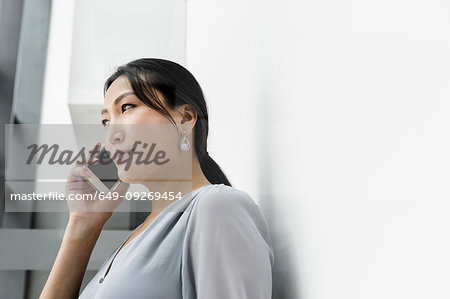 Businesswoman using smartphone against white wall in office